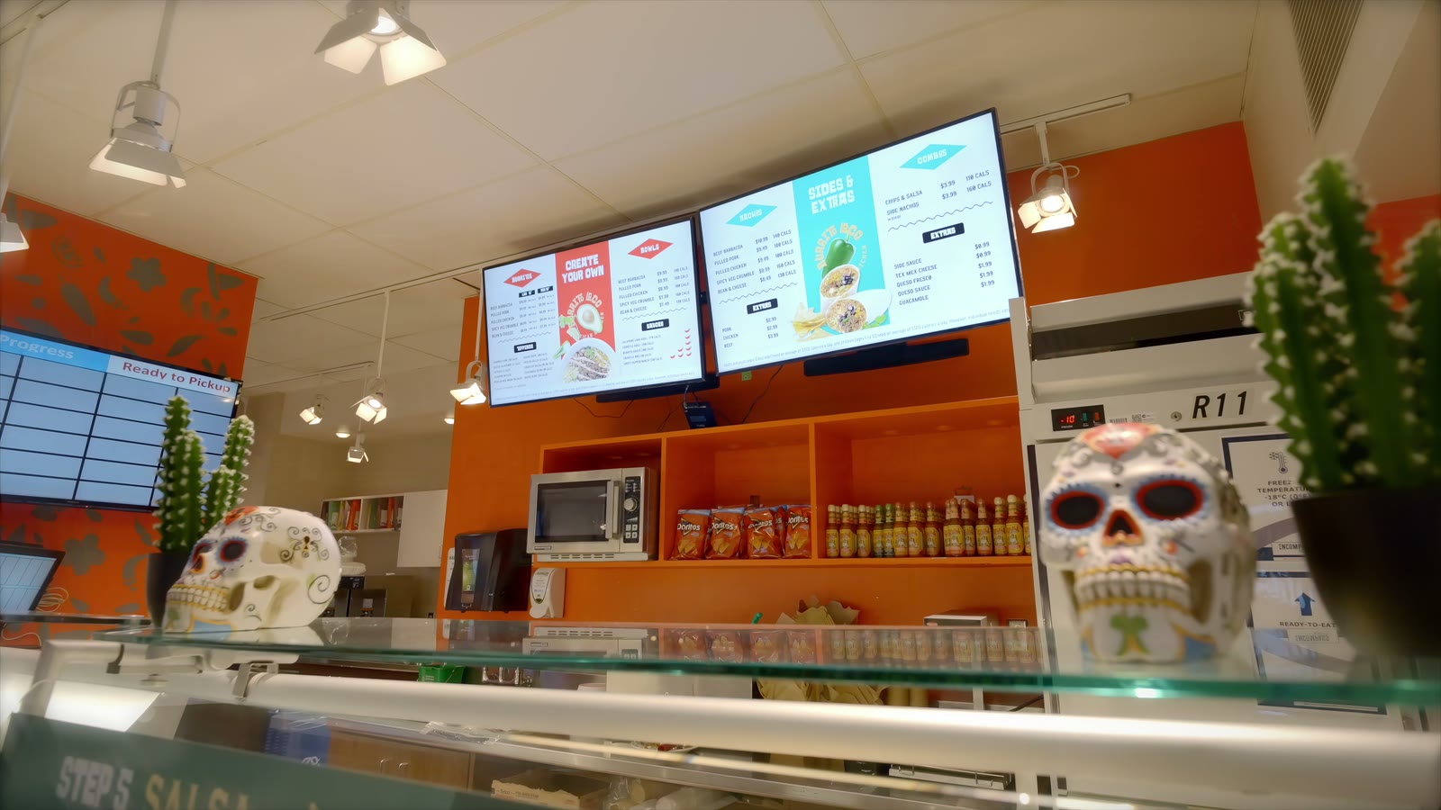 Burrito Loco counter with orange walls and digital menu boards