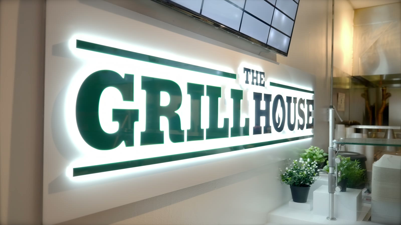 The lit Grill House sign over the counter