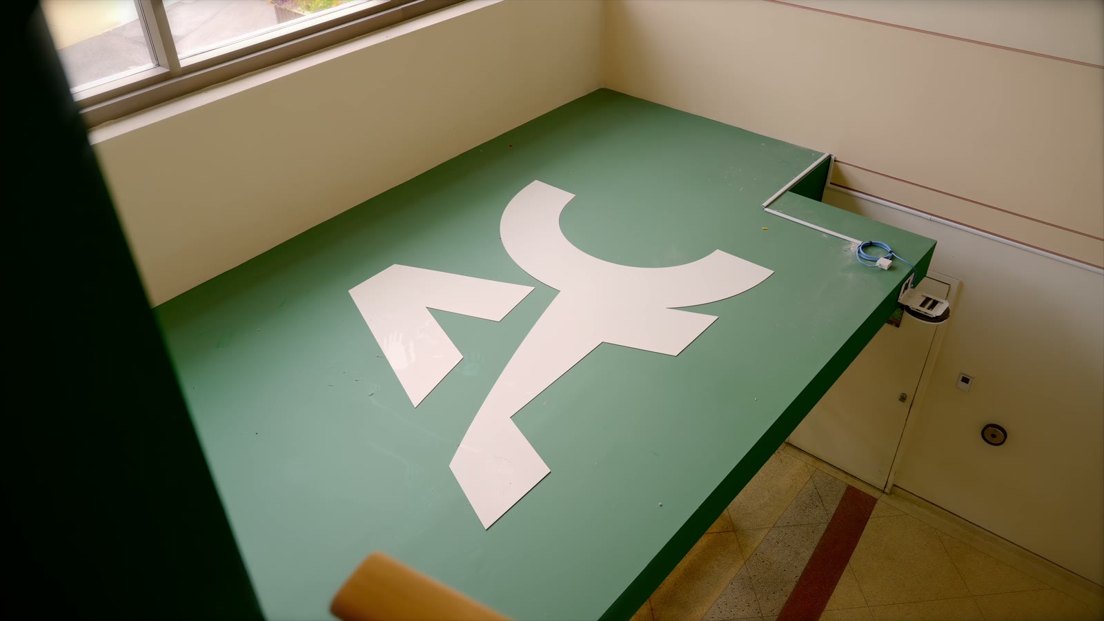 The AC mark in white on a green counter top
